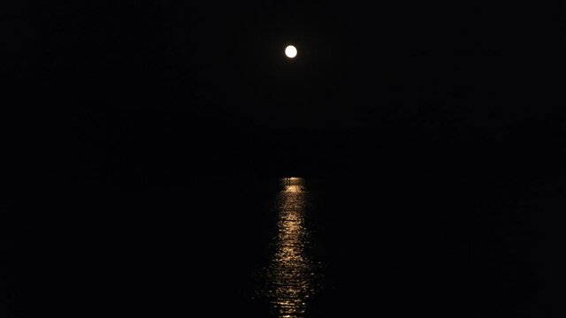 Moon path in the river or sea at night. Shining moonlight reflects on water. Black background
