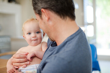 Father holding baby in kitchen