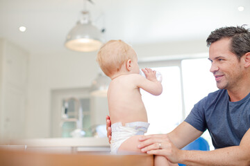Fototapeta premium Father feeding baby in kitchen