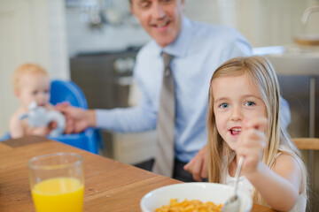 Father and children eating breakfast in kitchen