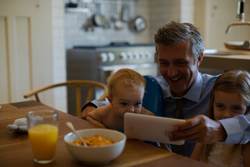 Father and children using digital tablet at table
