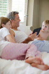 Fototapeta premium Father and children using digital tablet on bed