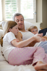 Obraz premium Father and children using digital tablet on bed