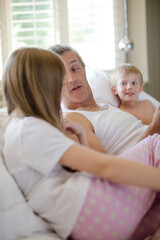 Father and children using digital tablet on bed