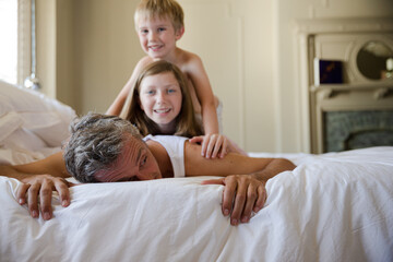 Father and children playing on bed