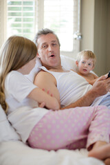 Obraz premium Father and children using digital tablet on bed