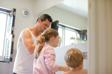 Fototapeta premium Father and children brushing teeth in bathroom