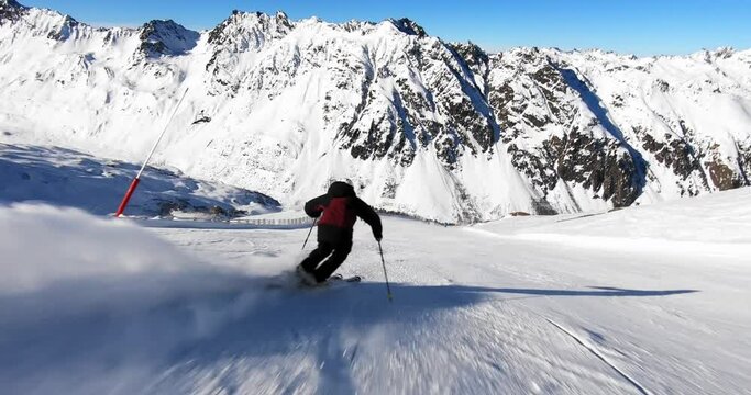 Full speed action skiing of young male skier, nice rhythmic short ski turns on a steep ski slope in Austria. Cinematic snow skiing in stunning winter alpine landscape in the Tyrolean mountains.