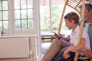 Father and son sitting in wicker chair