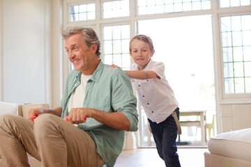 Obraz premium Boy pushing father on tricycle indoors