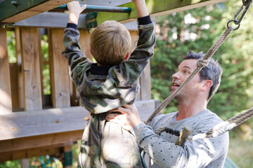 Father holding son on playset