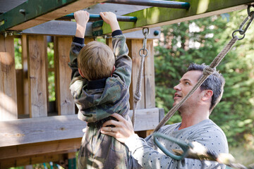 Father holding son on playset
