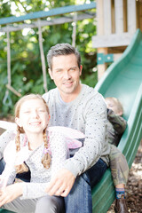 Father and children sitting on slide