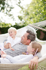 Obraz premium Father and children laying in hammock outdoors