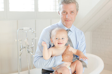 Father holding baby in bathroom