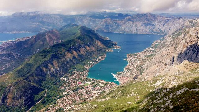 Bay of Kotor in Montenegro - aerial landscape of green Vrmac hill and mountains surrounding Boka on a sunny day under white clouds in the sky. Famous tourist destination on the Mediterranean coast.