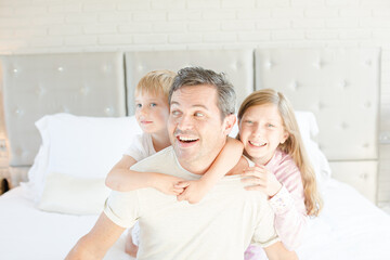 Father and children hugging in bedroom