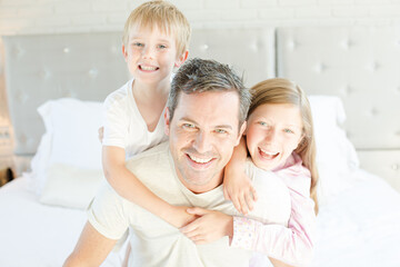 Obraz premium Father and children hugging in bedroom