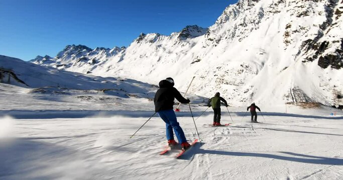 Three ski friends showing nice rhythmic ski turns with great skiing skills and style in beautiful winter alpine mountain landscape. Ski professionals performing a ski show in a austrian resort.