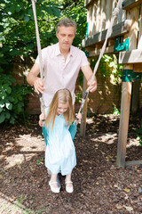 Naklejka premium Father pushing daughter in swing