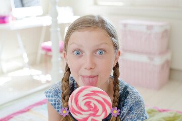 Girl licking lollipop in bedroom