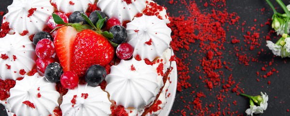 Delicious homemade red velvet cake with meringue and mascarpone cream on black background.
