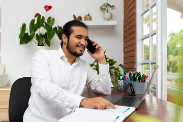 latino man with long hair in phone call with notebook and laptop