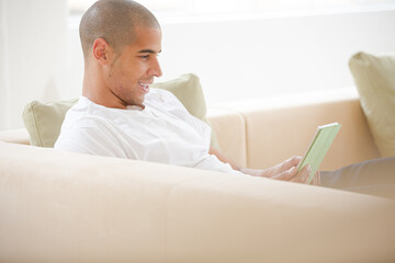 Obraz premium Man using digital tablet on sofa