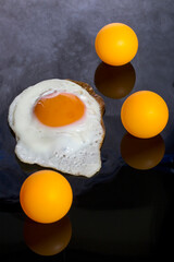 Still life with a roasted scrambled eggs and orange balls on an abstract background