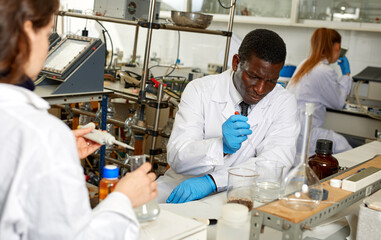 Portrait of proffesional male and female lab technicians with different test tubes