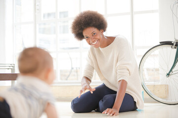 Fototapeta premium Mother watching baby boy crawl on floor