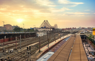 Howrah bridge with view of railway tracks and Kolkata cityscape at sunrise.