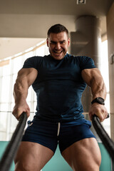 Obraz premium Handsome young muscular man of model appearance exercising arms in the gym 