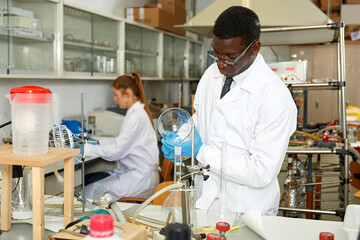 Serious man lab scientist in glasses working with reagents and test tubes in laboratory