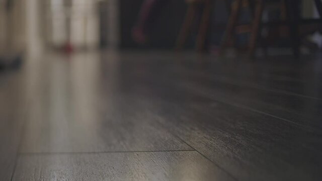 Close-Up Shot of Wood Floor as Person Walks in the Background