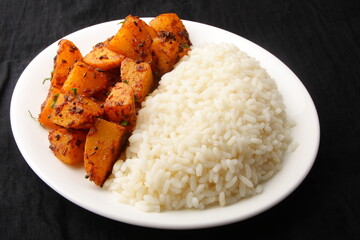 Homemade Asian vegetarian meal- healthy organic white rice served with spicy potato roast curry, Indian cooking.