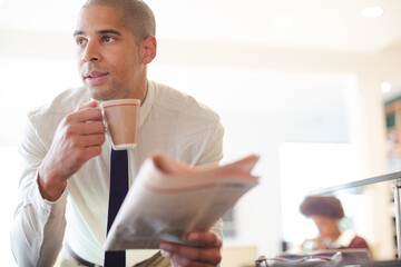 Businessman reading newspaper and drinking coffee