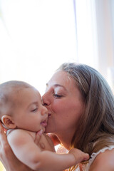 Obraz na płótnie Canvas Mother kissing baby boy's cheek
