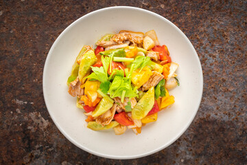 Moo Pud Preaw Wan, Thai food, sweet and sour sauce stir fried with pork, pineapple, tomato, cucumber, onion topped with celery in ceramic plate on rusty texture background, top view