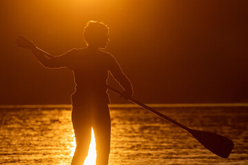 Girl on sup board with beautiful colored sunrise background mountains background