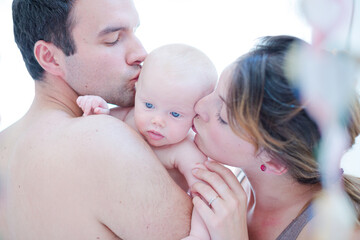 Parents kissing baby girl's cheeks