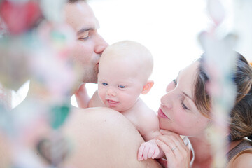 Parents kissing baby girl's cheeks