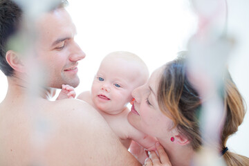 Parents kissing baby girl's cheeks