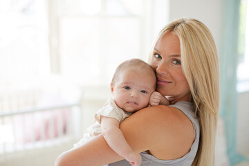 Mother holding baby girl in nursery