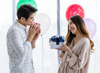 Lovely young Asian girl and boy couple happy and enjoy exchange gift boxes to other during...