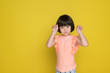 happy kid on yellow background, portrait asian child, little girl
