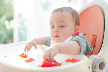 Baby boy eating gelatin dessert in high chair