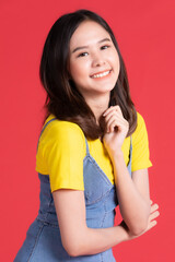 Asian girl Wear yellow shirt and short skirt pose in advertising and presenting goods and contents gesture with friendly smile face on red background.