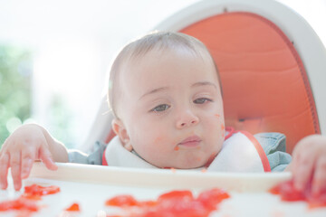 Baby boy eating gelatin dessert in high chair