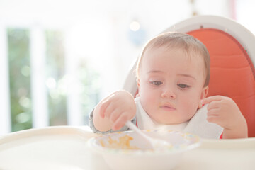 Baby boy eating in high chair